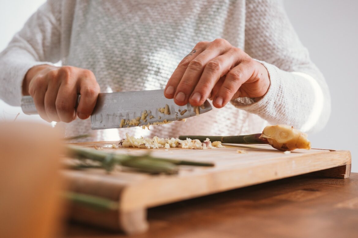 person holding knife slicing vegetable